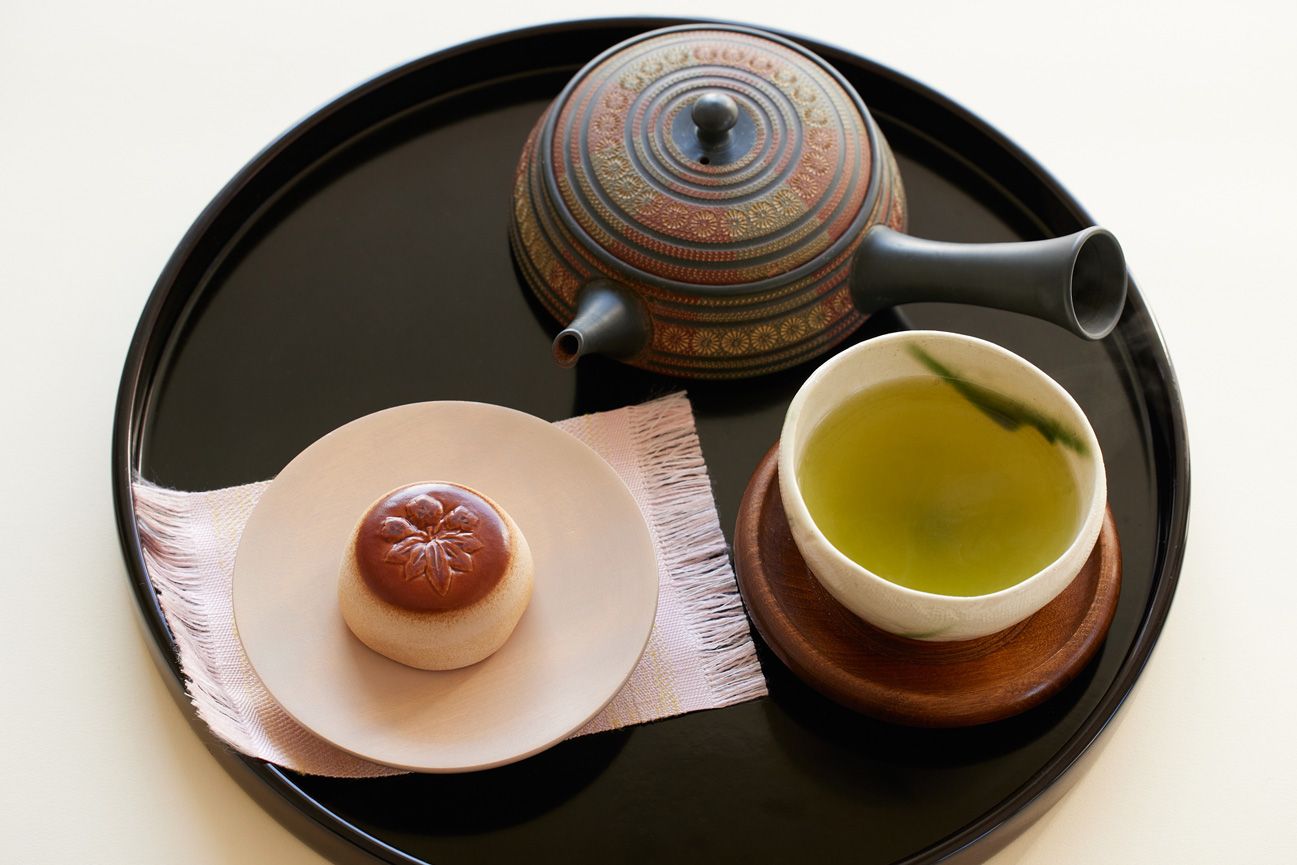Oribenishiki, a toasted Japanese-style cake filled with sweet potato paste with chopped chestnuts, and smooth red bean paste. Served alongside a kyusu (traditional Japanese teapot) filled with sencha green tea and chawan (tea bowl) on a single-serving bon (Japanese serving tray). (Confectionery provided by: Minamoto Kitchoan) 
