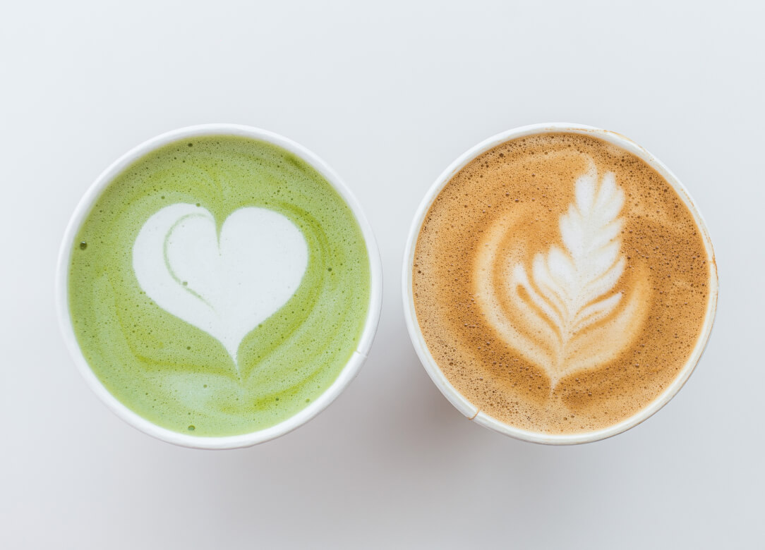 An image of 2 cups on a white background. One cup is full of matcha, and the other is filled with coffee.