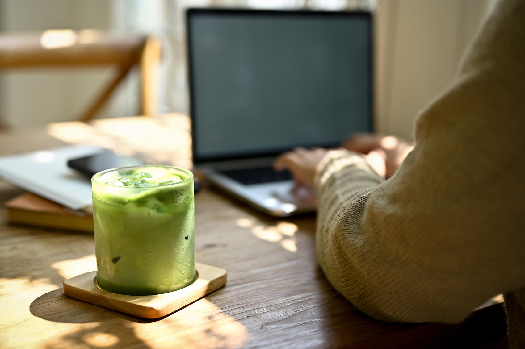 Image of a man working on a computer. There is a glass of matcha tea right next to him.