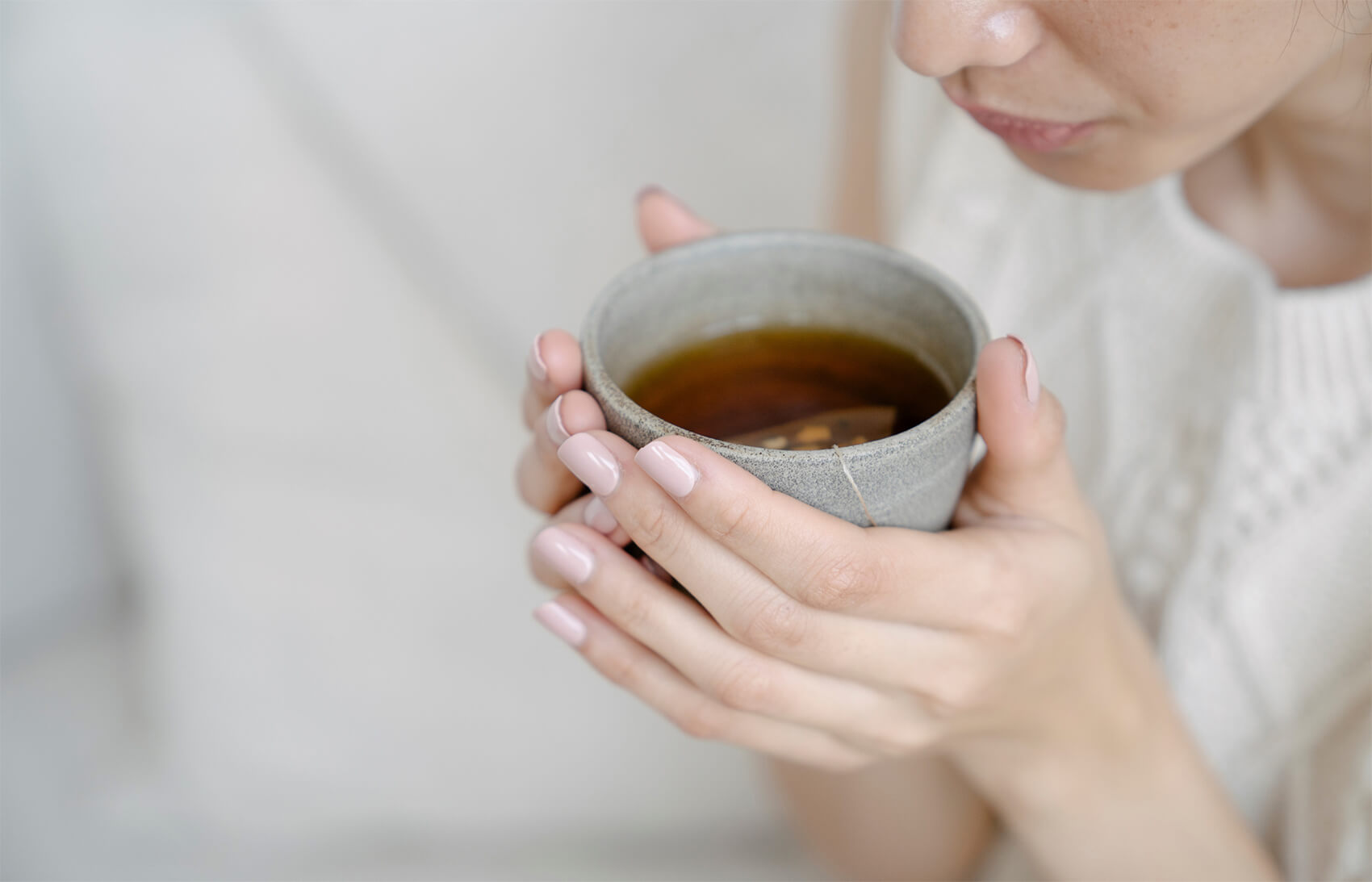 Image of a woman holding a cup of tea in her hands.