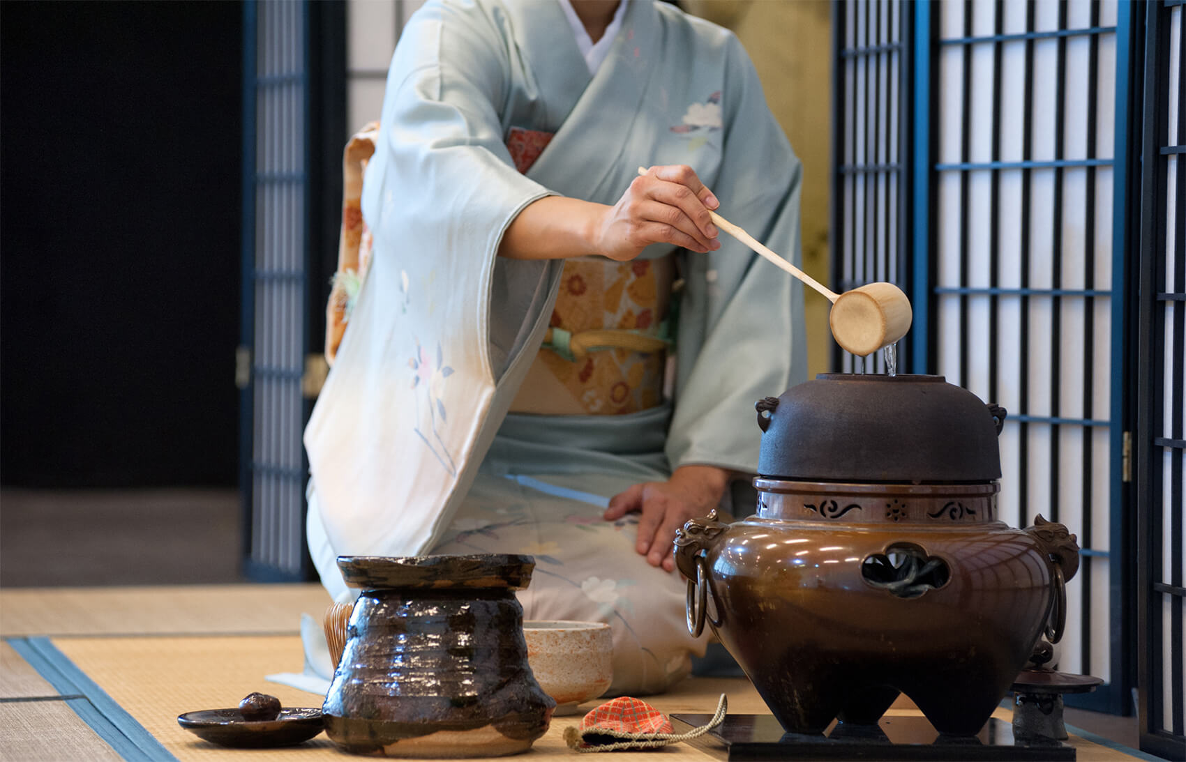 An image of a woman dressed in a traditional Japanese kimono, performing a tea ceremony.