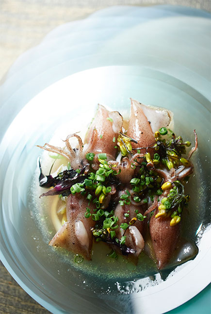 Photo of live hotaru ika squid are roasted and accented with nabana flower petals and leeks.