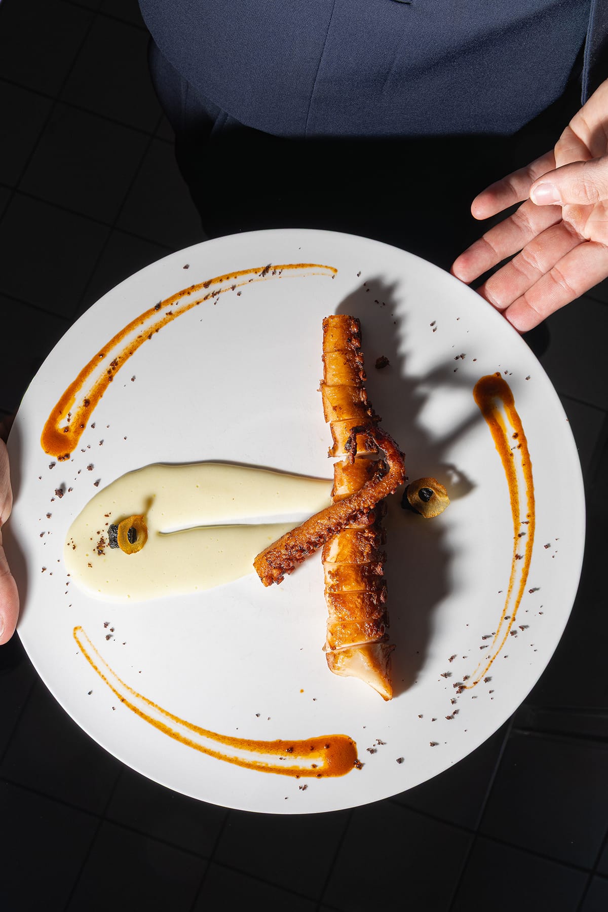 Pulpe: Poulpe cuit au four dans un court bouillon, tentacule rôtie à la plancha servi avec purée de pommes de terre, huile de pimenton, croûtons à l'encre de seiche et chips de pommes de terre